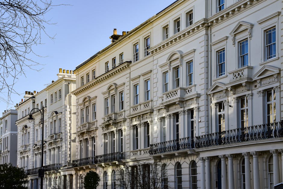 A wide street scene in Earls Court, SW7, showing lined pavements with pedestrians and a variety of commercial buildings on both sides, including a large store with colorful flags hanging outside. The 